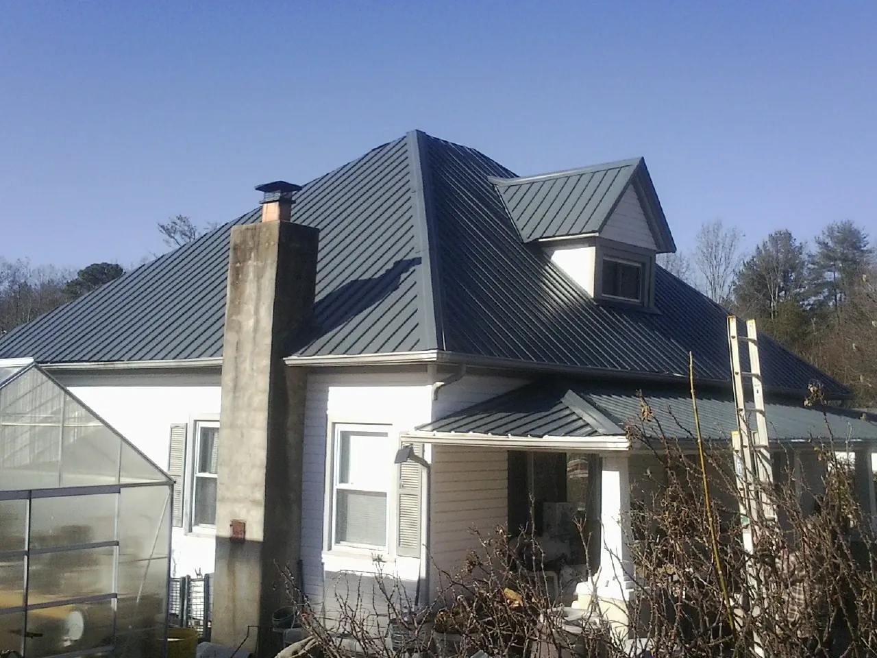 Dark blue standing seam metal roof on a white farmhouse with dormer — Slate & Tile Roof Repair by Roofing Brothers in Amsterdam