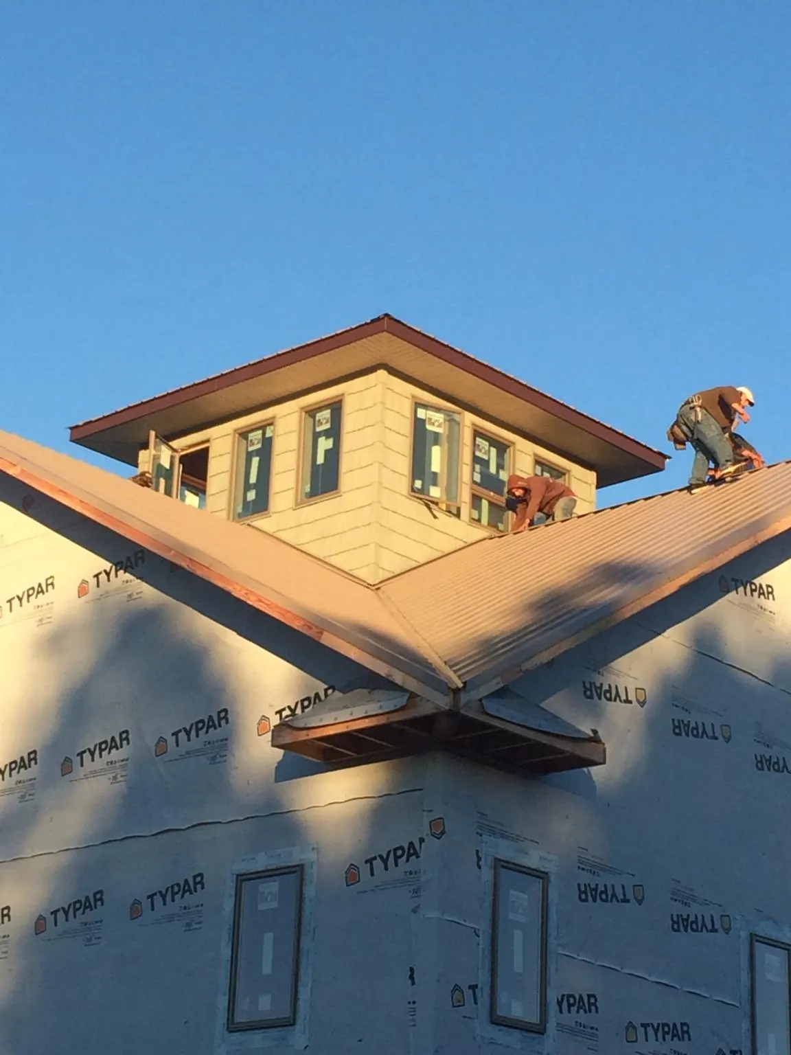 Roofers working around a rooftop cupola on a new metal roof at sunset — Roof Waterproofing in Amsterdam by Roofing Brothers